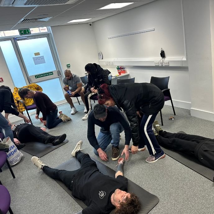 A group practising first aid on mats
